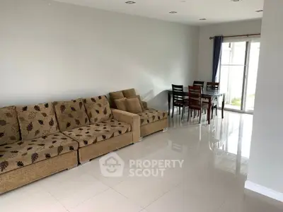 Spacious living room with modern furniture and dining area, featuring large windows for natural light.