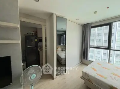 Modern bedroom with large windows and adjacent kitchen area in a high-rise apartment.