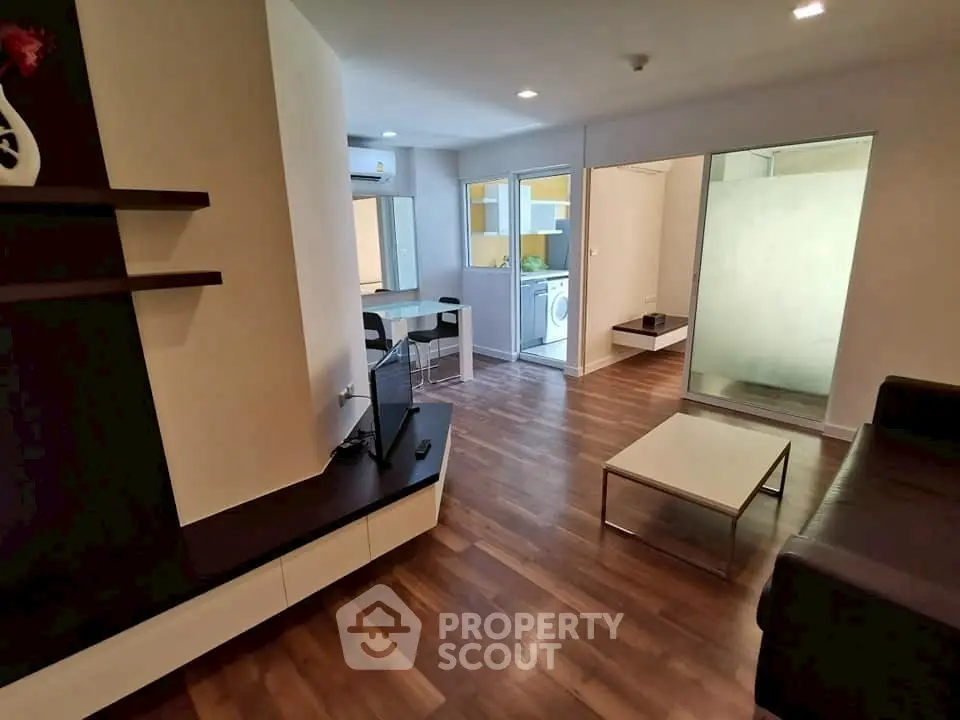 Modern living room with sleek wooden flooring and open kitchen layout