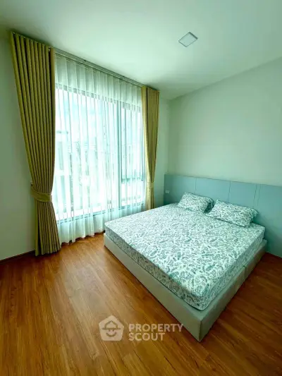 Bright and cozy bedroom with large window and elegant curtains, perfect for relaxation.
