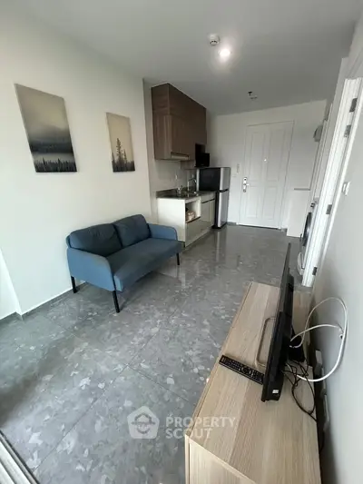 Modern living room with sleek kitchen, cozy sofa, and stylish decor in a contemporary apartment.