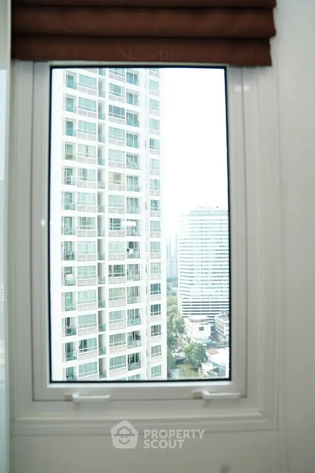Stunning cityscape view from a modern apartment window, showcasing high-rise buildings and urban landscape.