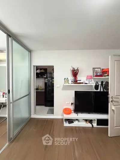 Modern living room with sleek TV stand and sliding glass doors leading to kitchen.