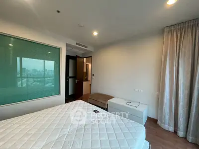 Spacious bedroom with city view and modern furnishings in a high-rise apartment.