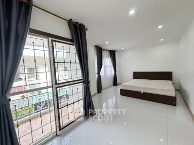 Spacious bedroom with large windows and modern decor in a bright, airy apartment.