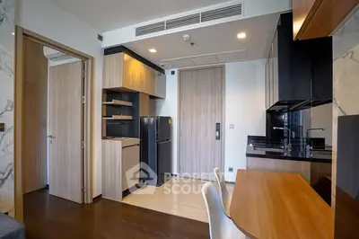 Modern apartment interior with sleek kitchen and dining area, featuring wood and black accents.