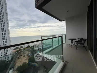 Stunning ocean view from a modern high-rise balcony with glass railing and seating area.