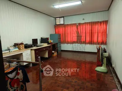 Spacious room with wooden flooring and red curtains, ideal for home office or creative studio setup.