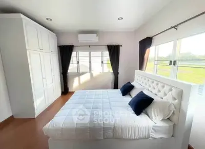 Spacious bedroom with large windows and elegant decor, featuring a plush bed and ample natural light.