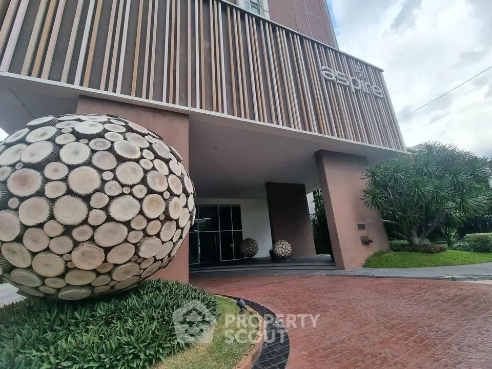Modern building entrance with unique wooden sphere sculptures and lush landscaping