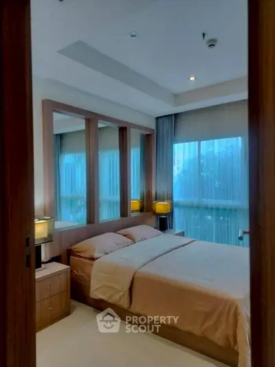 Cozy bedroom with large windows and warm lighting, perfect for relaxation.