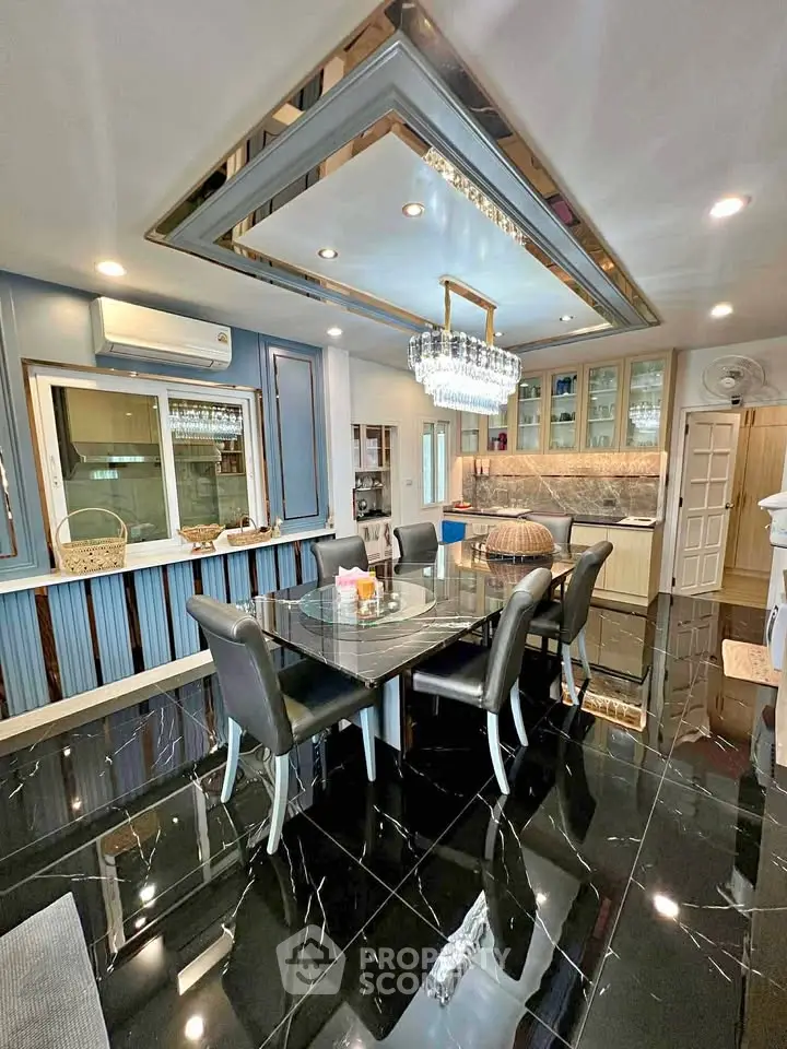 Luxurious dining area with elegant chandelier and modern decor, featuring sleek black flooring and stylish furniture.