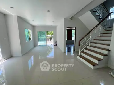 Spacious modern living room with glossy tile flooring and elegant staircase, perfect for family gatherings.