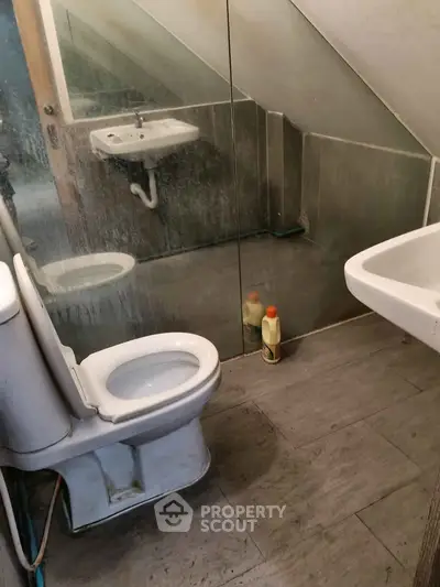 Compact attic bathroom with sloped ceiling and glass partition