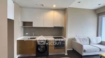 Modern kitchen with integrated appliances and cozy living area in open layout apartment.