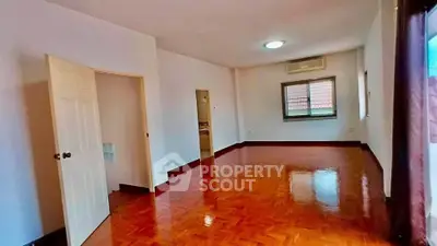 Spacious empty room with polished wooden floors and air conditioning, ideal for customization.