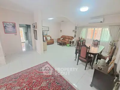 Spacious living room with elegant dining area and cozy seating, featuring large windows and classic decor.