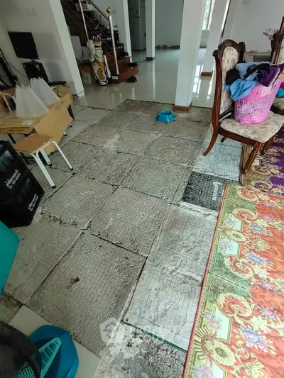 Spacious living area with partially removed flooring, showcasing renovation potential.
