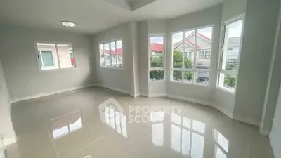 Spacious sunlit room with large windows and glossy tiled floors in modern home.