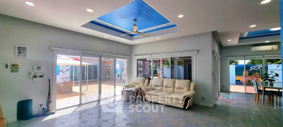 Spacious living room with modern design and large windows opening to a vibrant patio.