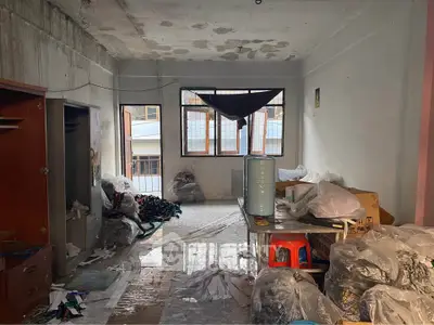 Spacious fixer-upper room with potential for renovation, featuring large windows and ample natural light.