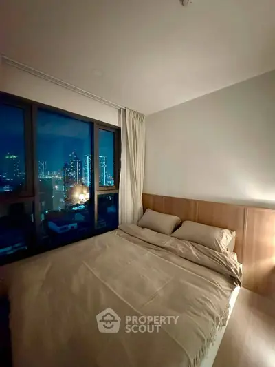 Cozy bedroom with city skyline view through large window, perfect for urban living.