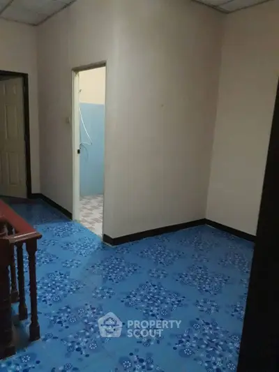 Spacious hallway with vibrant blue tiled flooring and access to adjacent rooms.