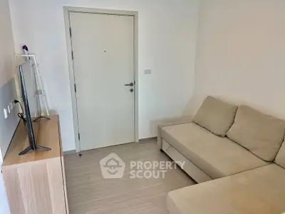 Cozy living room with modern sofa and flat-screen TV, perfect for relaxation.