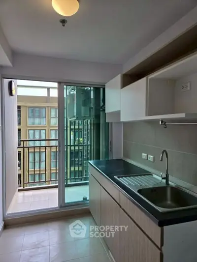 Modern kitchen with sleek cabinetry and balcony access in a contemporary apartment.