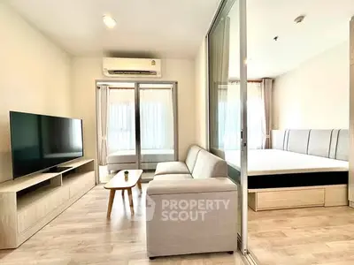 Modern living room with sleek furniture and glass partition leading to a cozy bedroom.