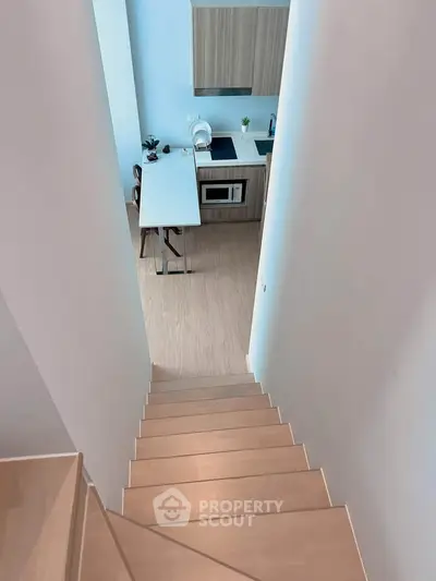 Modern kitchen with sleek design and wooden flooring viewed from staircase.
