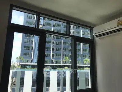 Modern apartment window view with air conditioning and cityscape backdrop.
