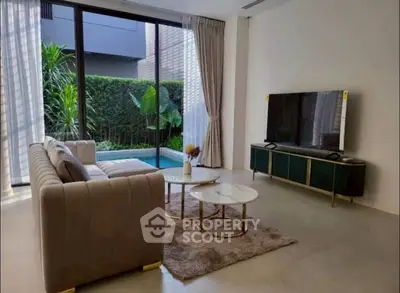 Luxurious living room with pool view, elegant sofa, and modern TV setup.