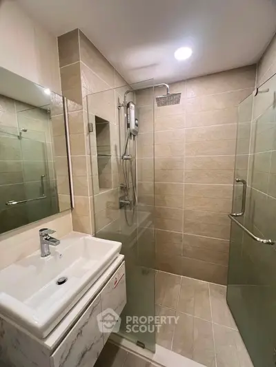 Modern bathroom with glass shower enclosure and sleek vanity in a contemporary home.