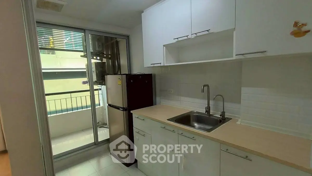 Modern kitchen with sleek cabinetry and balcony access in urban apartment.