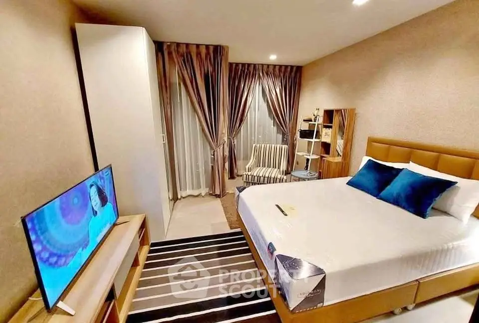 Modern bedroom with stylish decor, featuring a cozy bed, TV, and elegant curtains for a comfortable living space.
