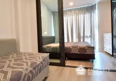 Spacious and well-lit bedroom with large mirror reflecting a comfortable bed, elegant curtains, and a cozy ambiance.