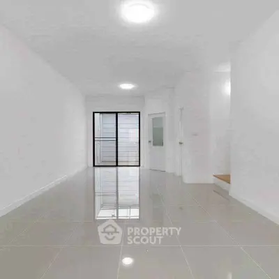 Spacious modern living room with glossy tiled floors and large windows.