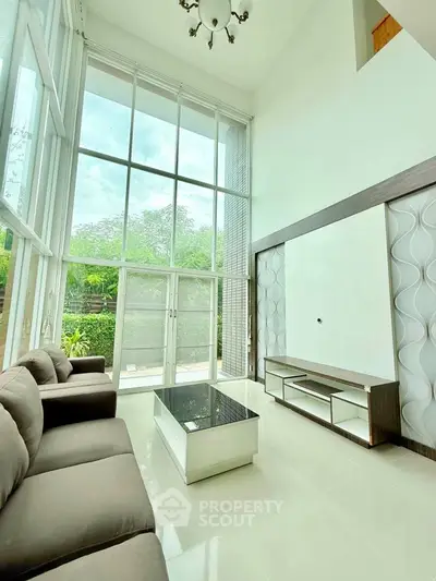 Spacious living room with high ceilings and large windows offering abundant natural light.