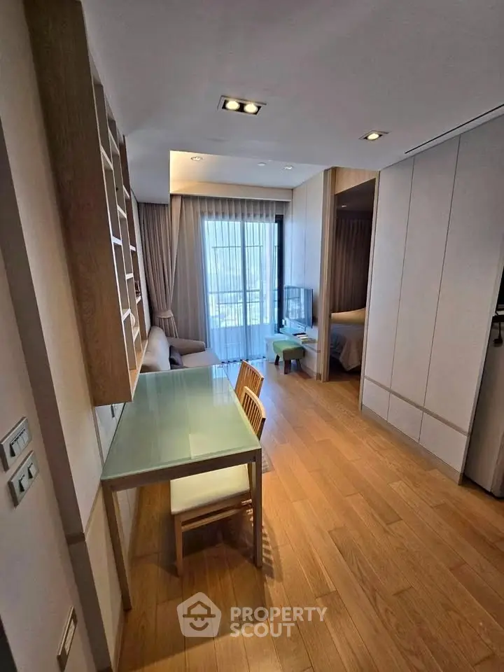 Modern apartment interior with wooden flooring, stylish furniture, and natural light from large windows.