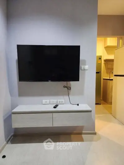 Modern living room with wall-mounted TV and sleek cabinetry in a stylish apartment.