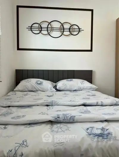 Cozy bedroom with nautical-themed bedding and modern wall art, perfect for a serene retreat.