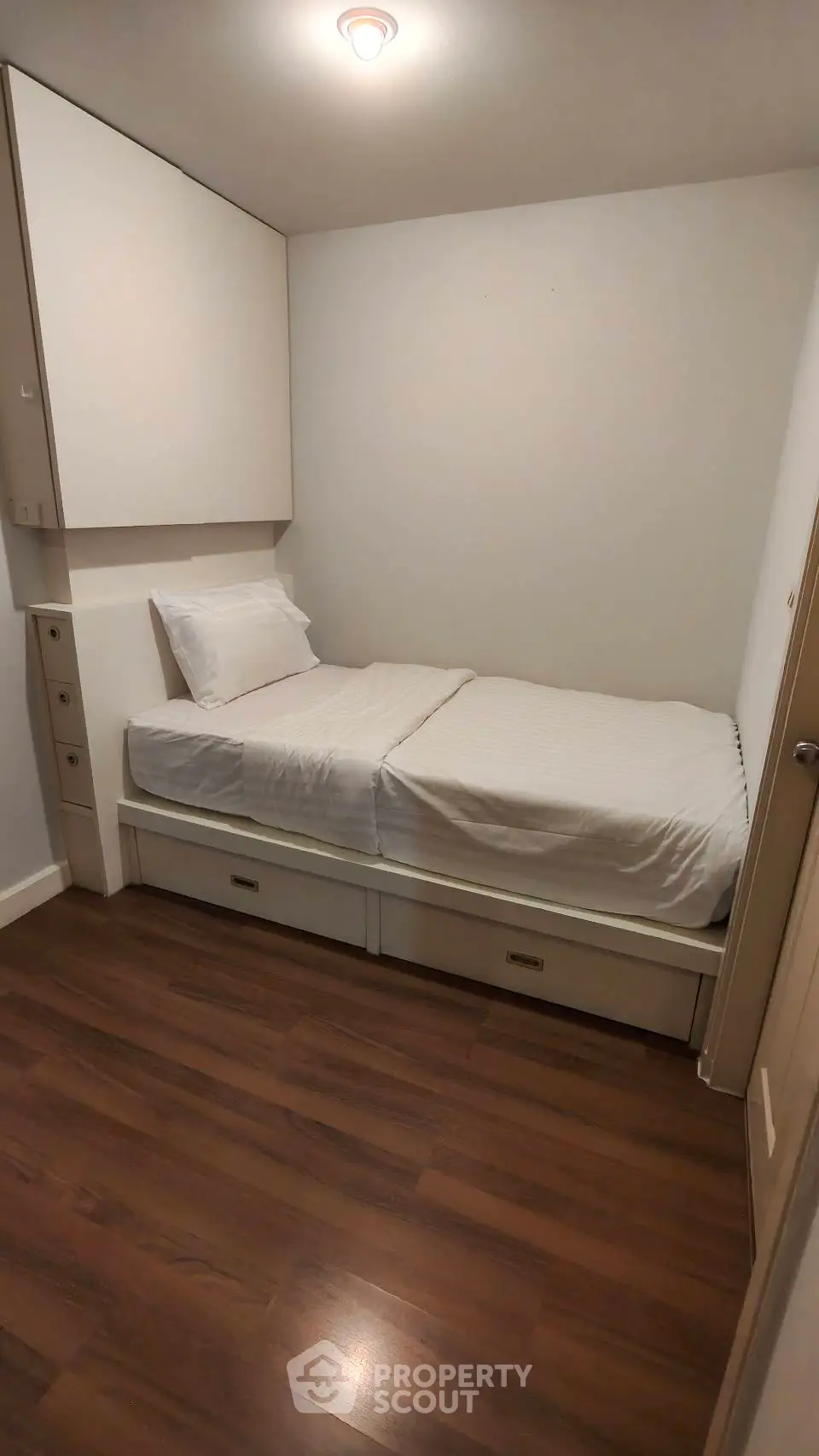 Cozy small bedroom with single bed and wooden flooring, perfect for minimalist living.
