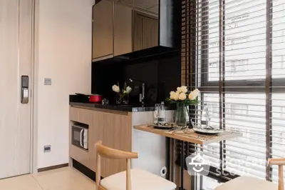 Modern kitchen with sleek black countertops, integrated appliances, and a cozy dining area bathed in natural light from the window.