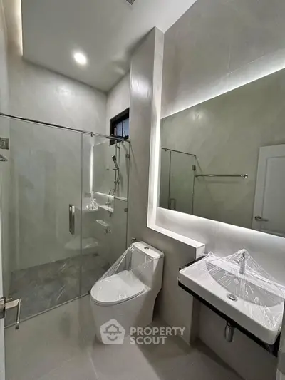 Modern bathroom with glass shower and sleek fixtures in contemporary home.