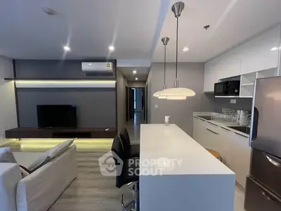 Modern open-layout living room and kitchen with sleek design and contemporary lighting.
