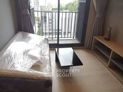 Modern living room with balcony view, featuring a wrapped sofa and sleek coffee table.
