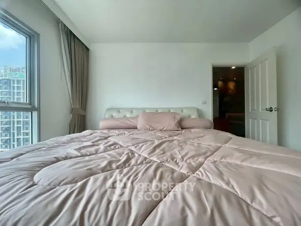 Spacious bedroom with large window offering city views and elegant decor.