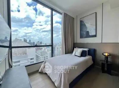 Modern bedroom with stunning city view and large windows in high-rise apartment.