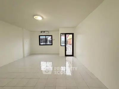 Spacious empty living room with tiled floor and large windows for natural light.